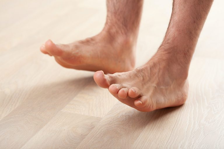 man doing flatfoot correction gymnastic exercise standing on heel at home